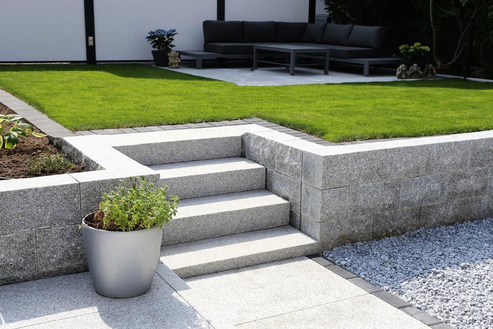 A potted plant sits next to a set of stairs in a garden