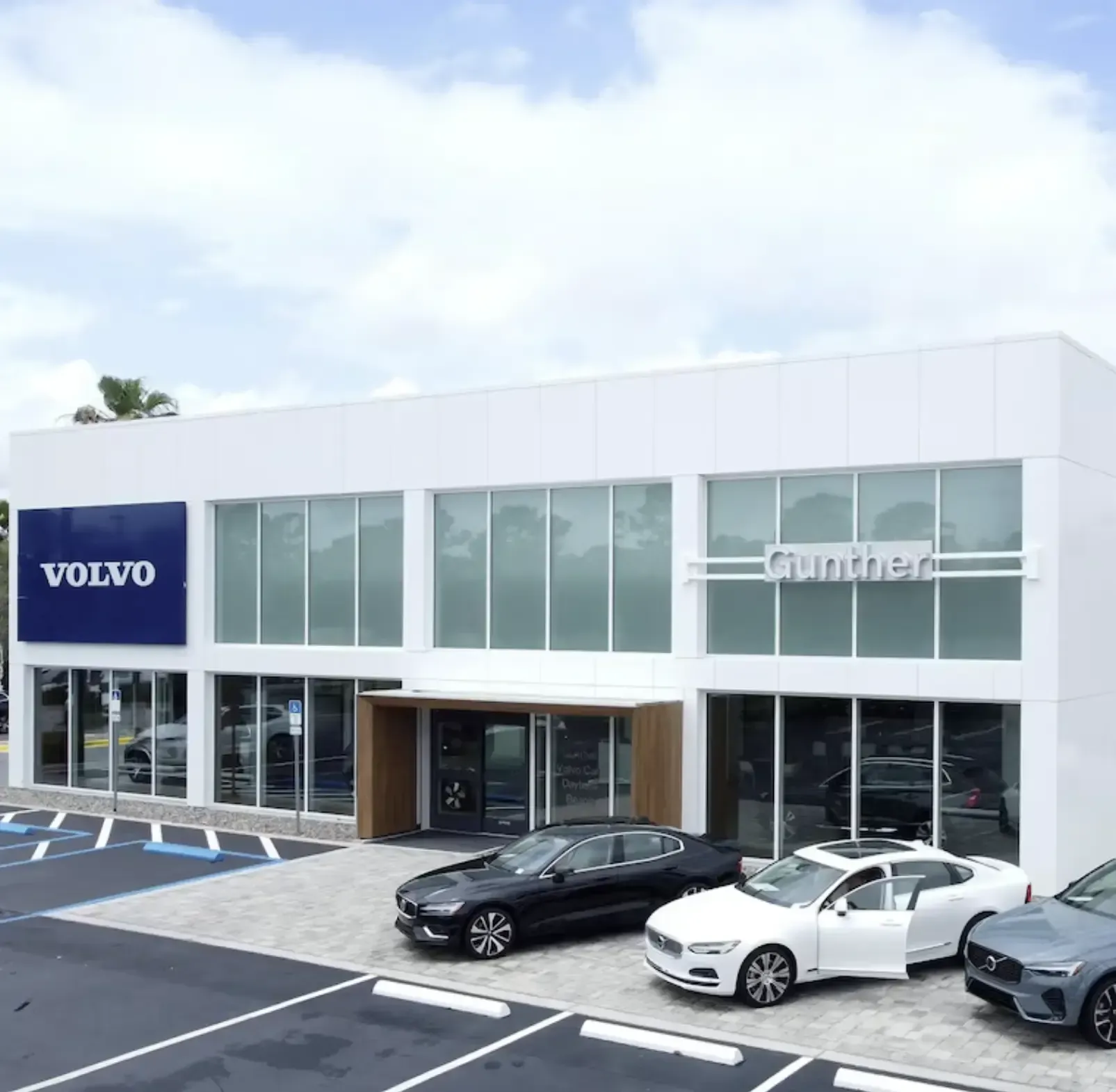 Volvo dealership with cars parked out front, a large sign with the Volvo logo, and the name 