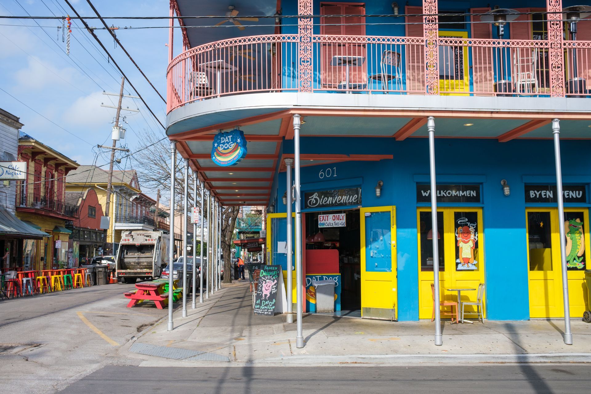 A blue and yellow building with a balcony in the middle of a city street.
