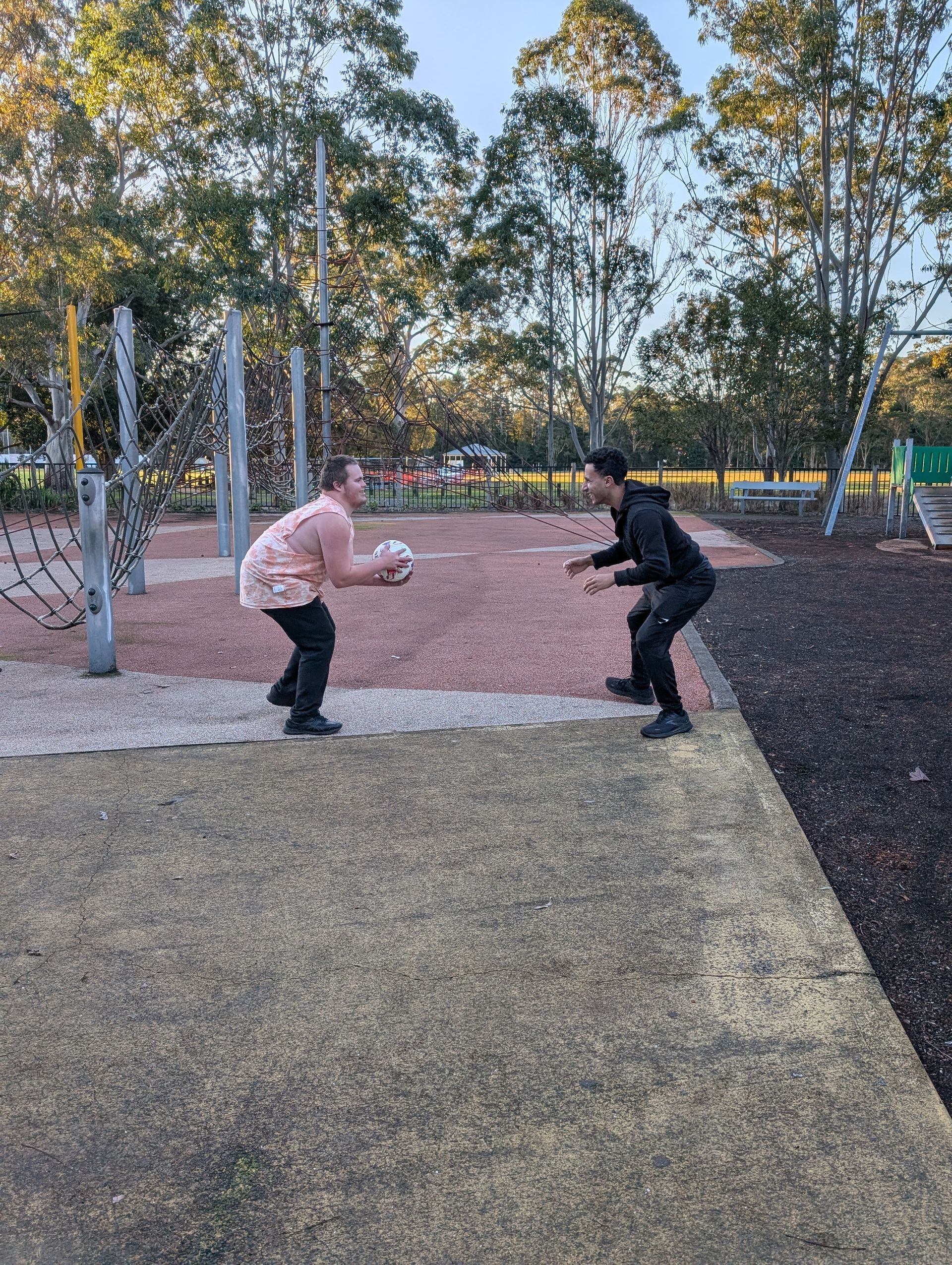 Two people in a park, one tossing a ball to the other. Playground in the background —True Form Fitness In Gwandalan, NSW