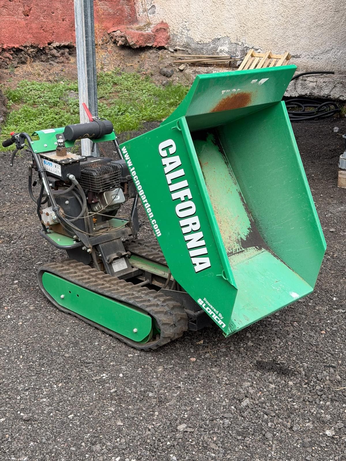 Spazzaneve verde California sul pavimento, ripreso di lato con il coperchio del camino staccato lì vicino.
