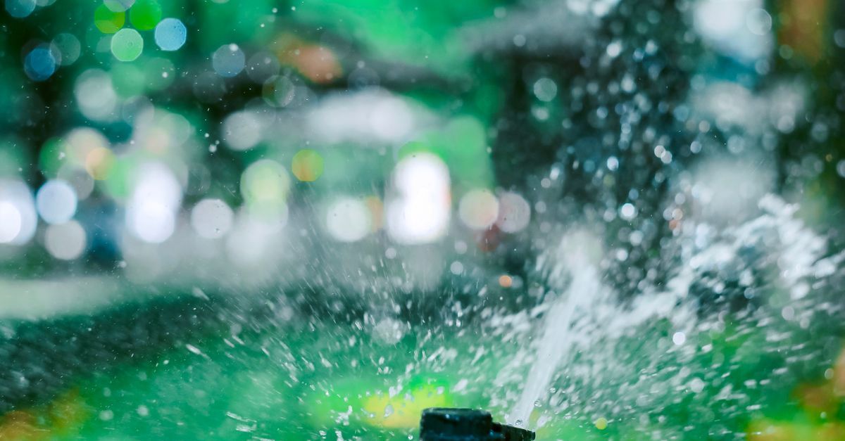 Lawn sprinkler spraying water on a green residential lawn