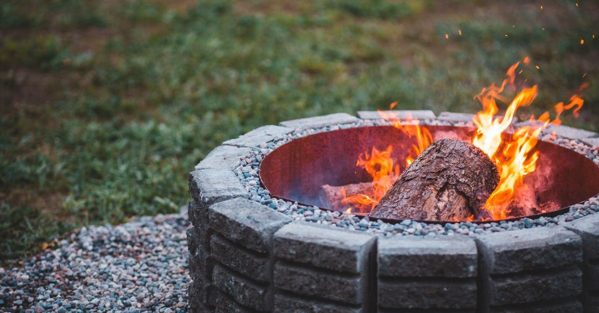 Stone fire pit with a crackling fire in a backyard
