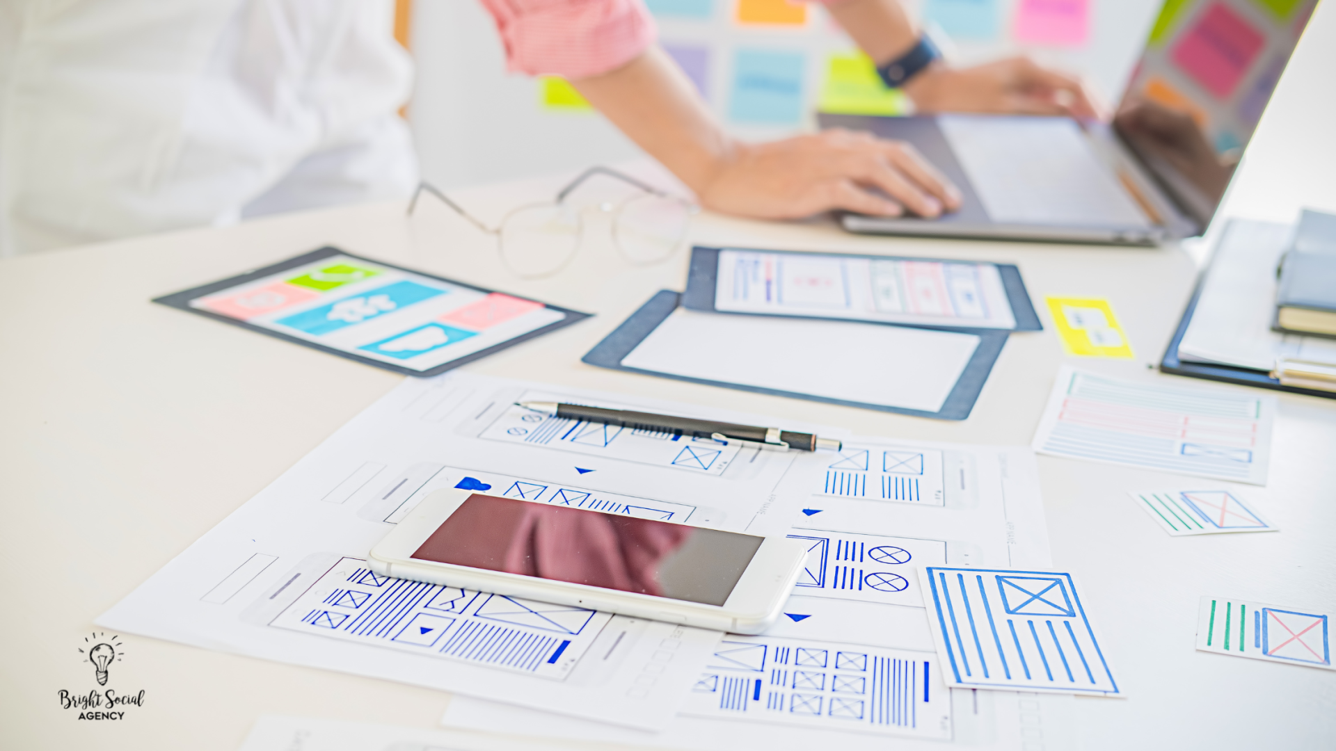 Person working on laptop with mobile app mockups, tablet, and smartphone.