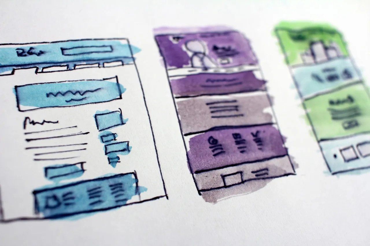 Watercolor sketches of three website page layouts, each with different colored sections: blue, purple, and green.