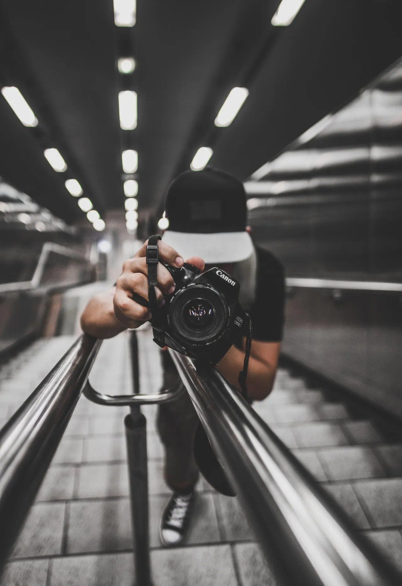 Photographer with camera on a staircase, holding the camera towards the viewer.