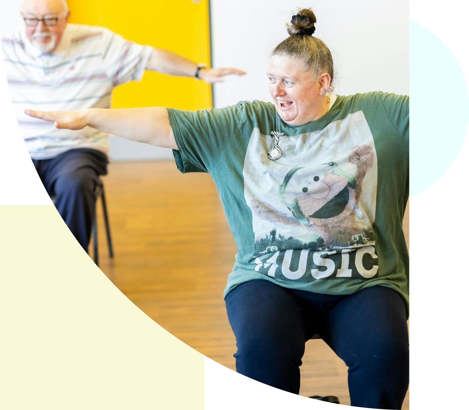 A woman wearing a green shirt that says music is sitting in a chair with her arms outstretched.