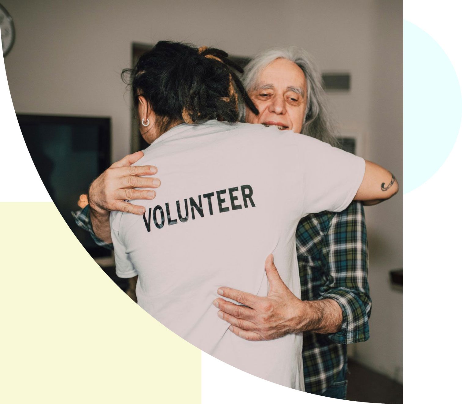 A woman wearing a volunteer shirt is hugging another woman.