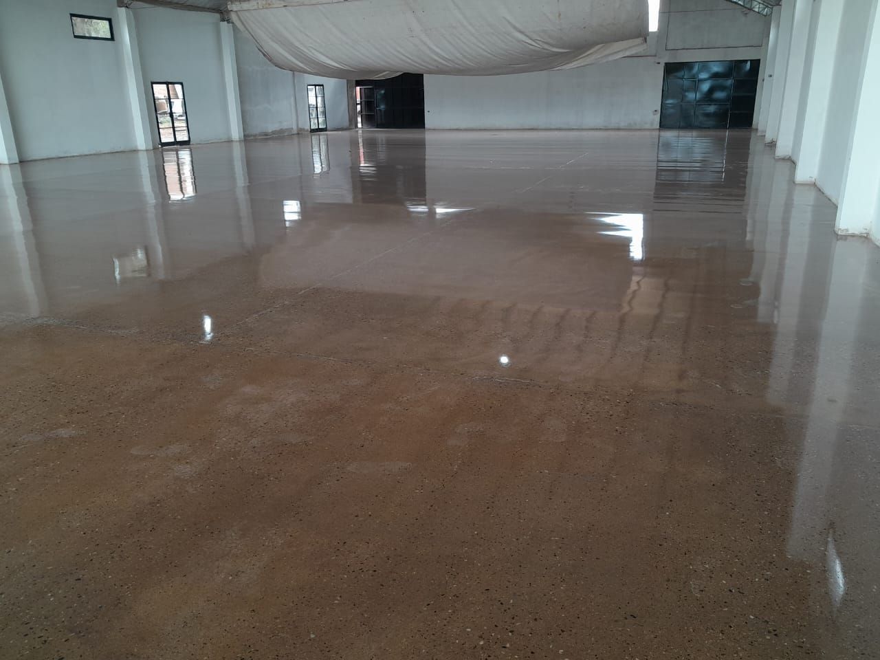 Pasillo interior vacío con un suelo mojado y brillante que refleja el techo y las paredes.