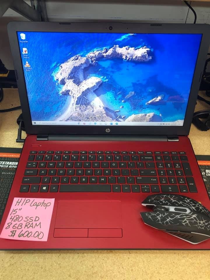 Red HP laptop with blue ocean wallpaper, sticky note, and wireless mouse on a desk