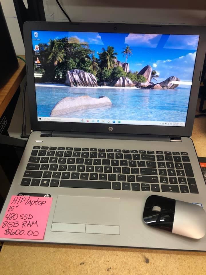 HP laptop on a desk with beach wallpaper, sticky note, and wireless mouse