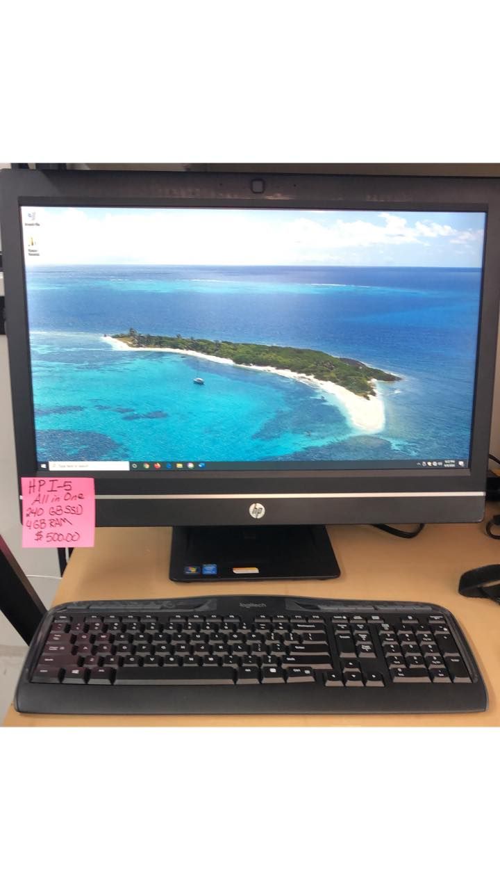 Desktop computer with keyboard showing a tropical island wallpaper on the monitor