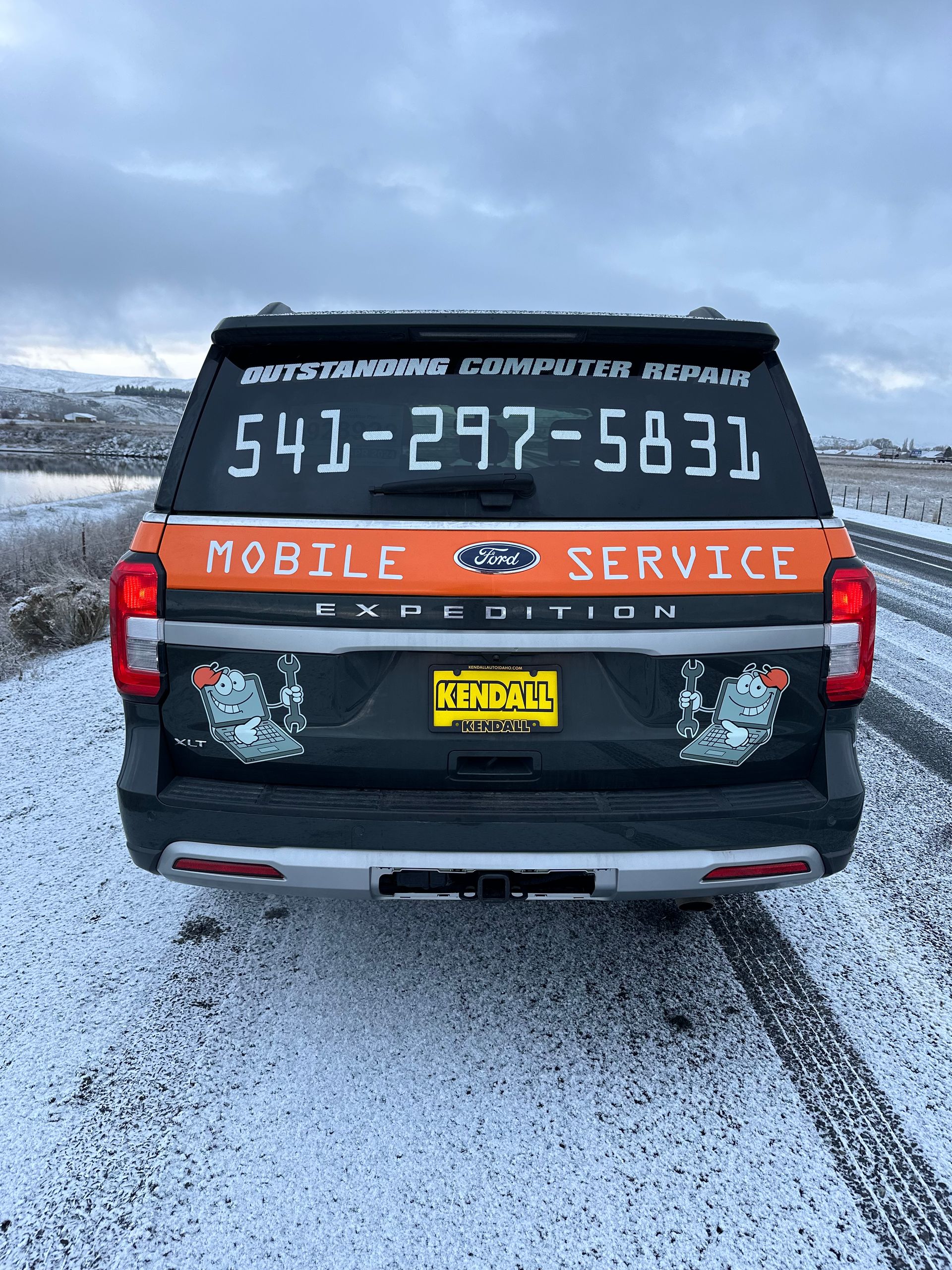 Black pickup truck with “Mobile Service” lettering and phone number parked on a snowy road