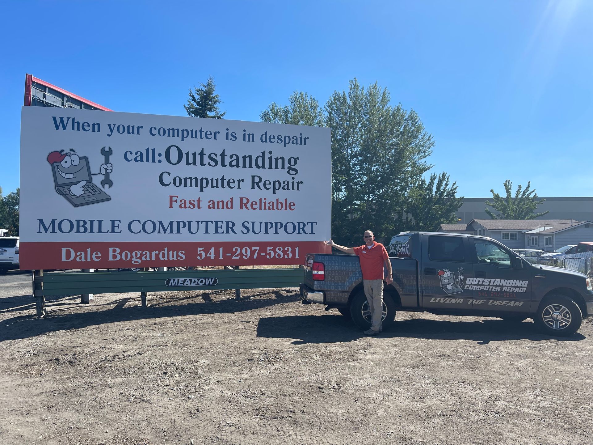 Mobile computer repair truck and billboard sign beside a man in a red shirt outdoors