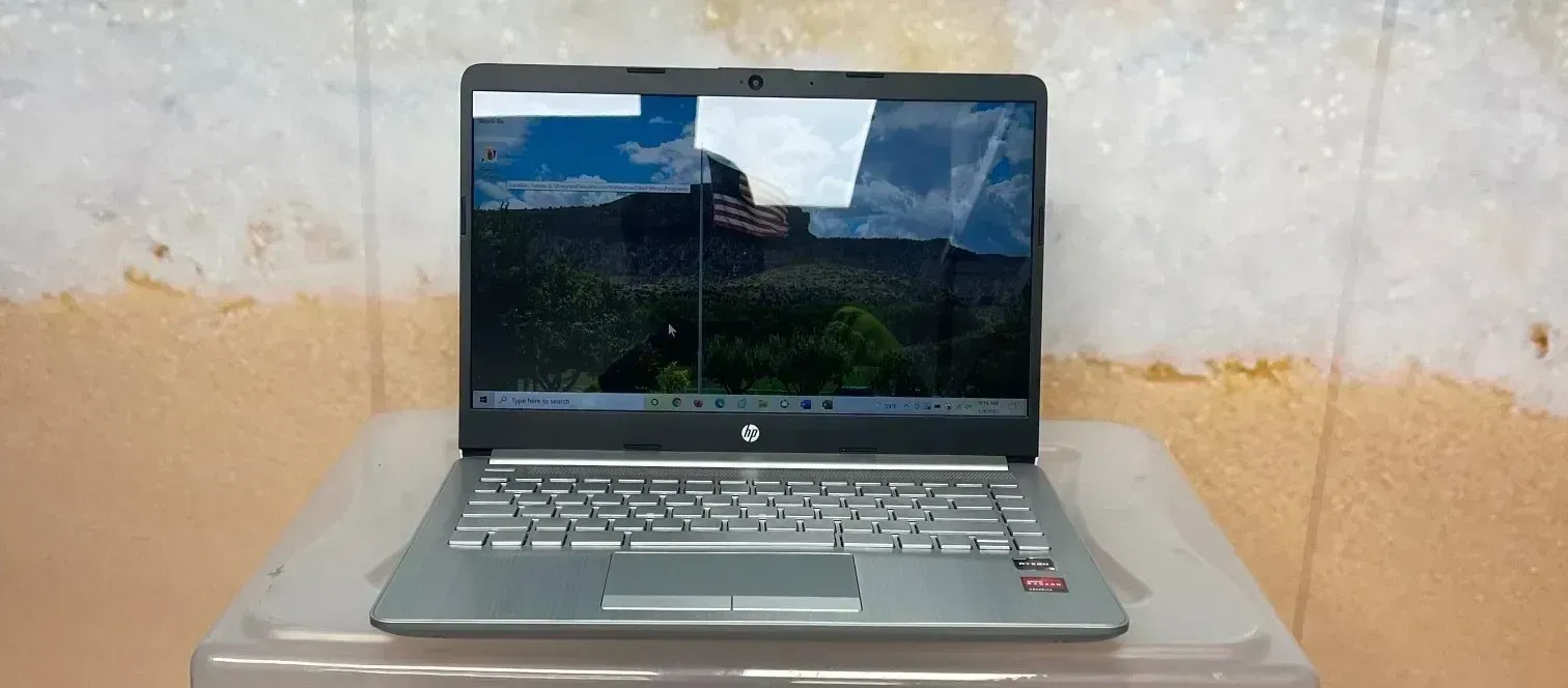 Gray laptop on a white table in front of a textured beige wall.