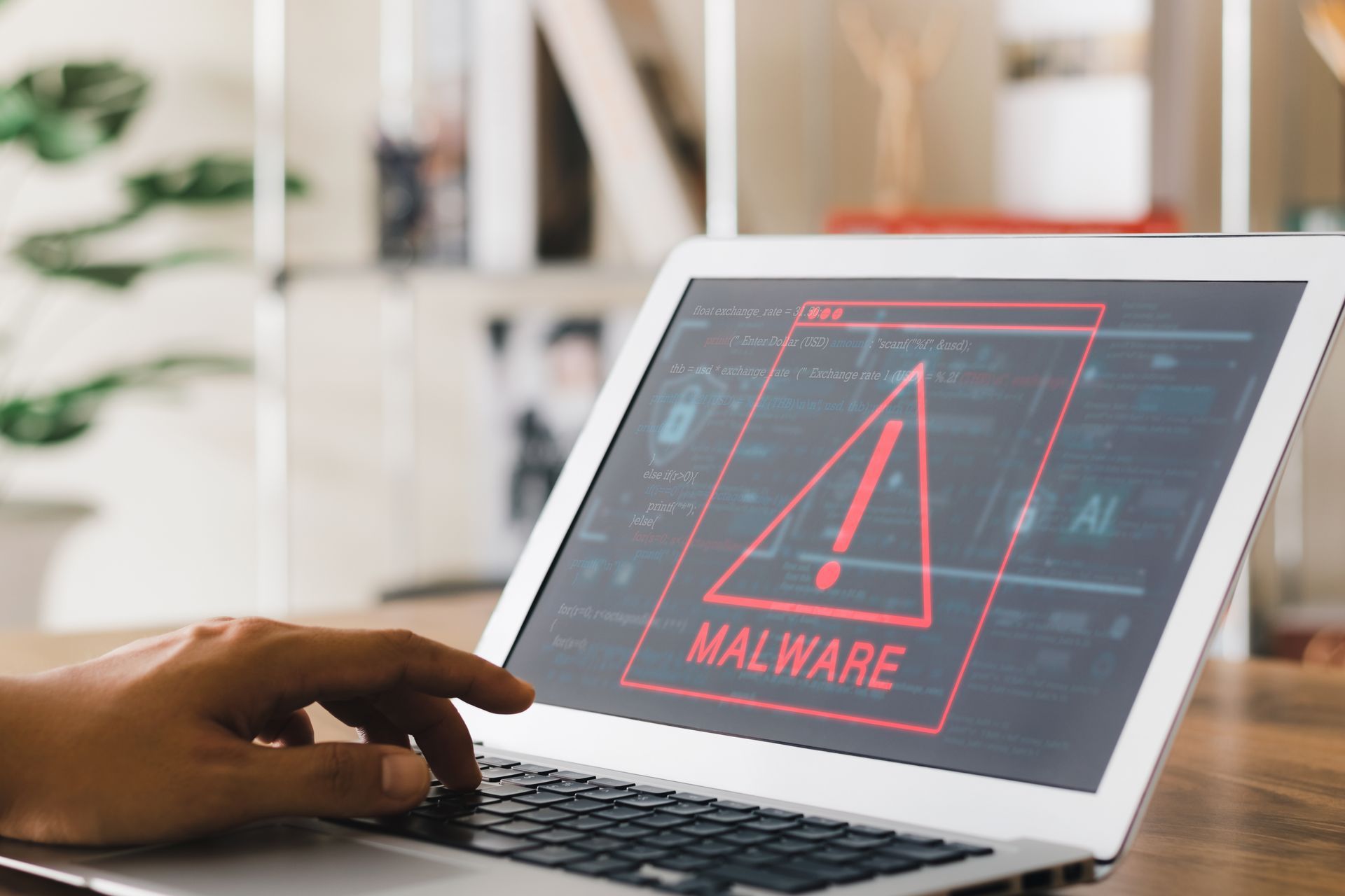 Person using a laptop displaying a red malware warning on screen