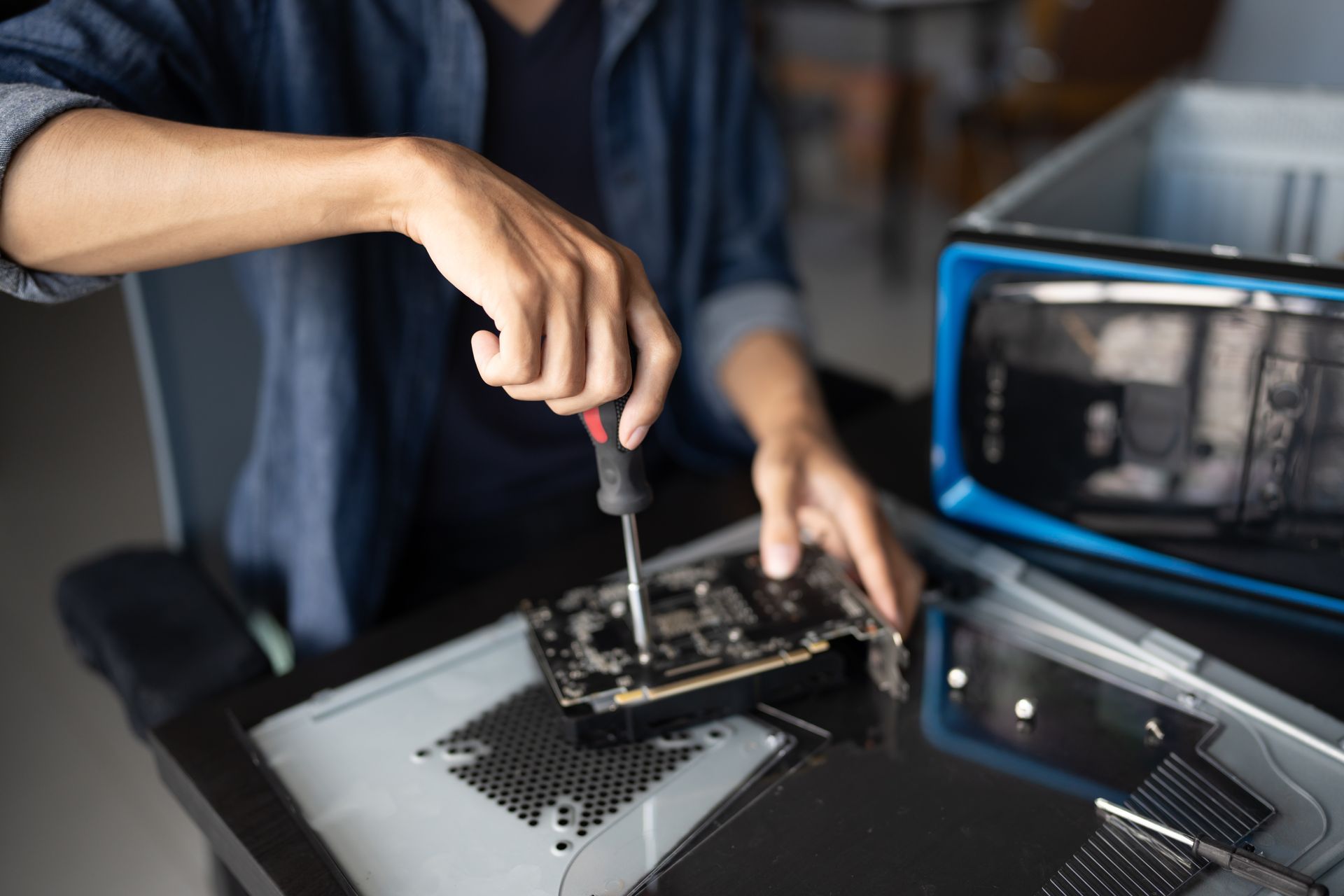 Person using a screwdriver to repair a computer motherboard on a workbench