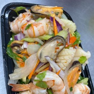 Assorted seafood salad with shrimp, mussels, and vegetables in a black container