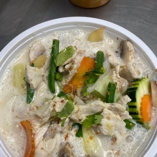 Bowl of creamy soup with chicken and mixed vegetables, including carrots, green beans, and zucchini.