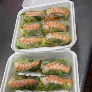 Two takeout containers of salmon sushi rolls on a metal table