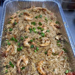 Tray of shrimp fried rice topped with chopped green onions in a foil pan