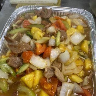 Tray of mixed stir-fried vegetables and meat with onions, carrots, peppers, and pineapple pieces