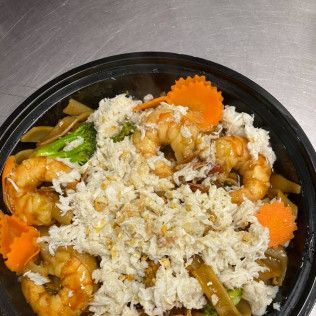 Bowl of shrimp fried rice with peas and carrot slices on a metal tray