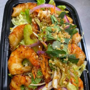 Takeout tray of shrimp stir-fry with vegetables, red onions, herbs, and noodles