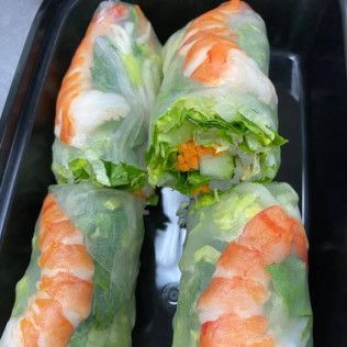 Four fresh spring rolls with shrimp and lettuce in a black takeout tray