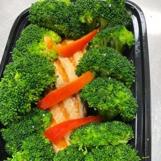 Broccoli and red pepper strips on a sandwich in a black takeout container