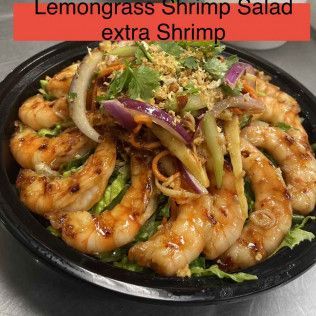 Lemongrass shrimp salad with extra shrimp in a black bowl, topped with herbs and sliced onions