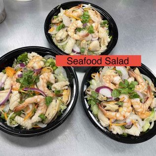 Three bowls of seafood salad with shrimp, vegetables, and greens on a light surface