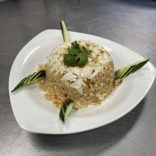 Rice and shrimp dish molded on a plate, garnished with cucumber slices and cilantro.