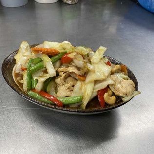 Stir-fried vegetables and chicken on an oval plate on a stainless steel counter