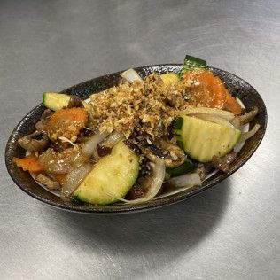 Grilled vegetable platter with zucchini, onions, mushrooms, and orange pepper on a black oval plate