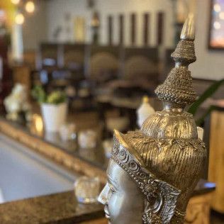 Golden Buddha statue in a softly blurred indoor setting with warm décor and seating in the background