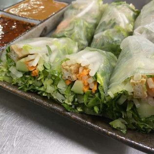 Fresh vegetable spring rolls on a tray with dipping sauces in small metal cups