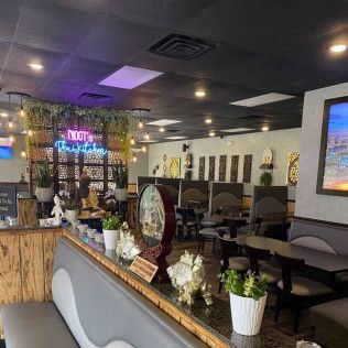 Modern restaurant interior with booths, neon sign, plants, and a bar counter