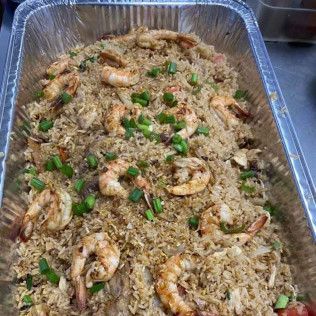 Foil tray of shrimp fried rice topped with chopped green onions