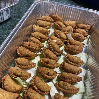 Tray of breaded fried appetizers arranged on lettuce leaves in a foil pan.
