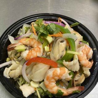 Shrimp and mussel salad with vegetables on a black takeout container