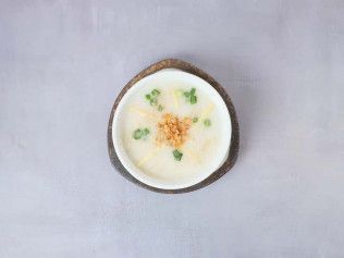 Top-down view of a bowl of creamy soup topped with herbs and grated cheese