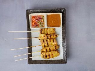 Plated grilled skewers with two dipping sauces on a rectangular black dish