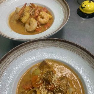 Two bowls of curry with rice and fried shrimp on a table