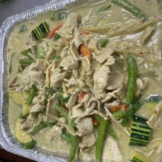 Tray of creamy chicken and vegetables, with zucchini and asparagus in green sauce