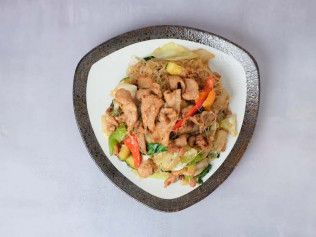 Heart-shaped bowl of stir-fried meat and vegetables on a white plate