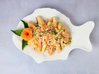 Fish-shaped white plate with pasta salad, garnished with orange flower and green leaves