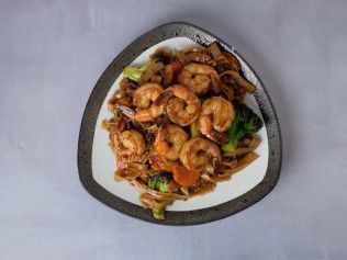 Plated shrimp stir-fry with vegetables on a white background