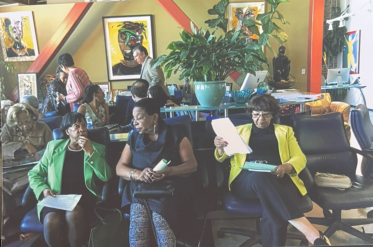 People seated indoors reading papers in a colorful lounge with artwork and plants