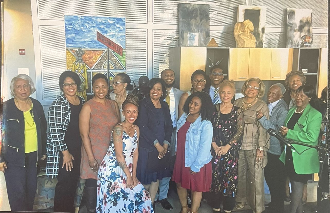 Group of people posing indoors in front of colorful artworks and sculptures